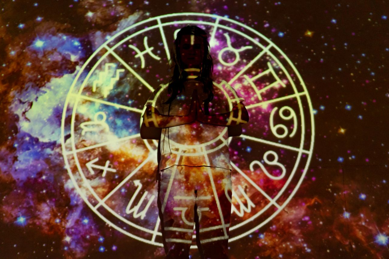 Services Silhouette of a person with celestial astrology symbols against a cosmic background.